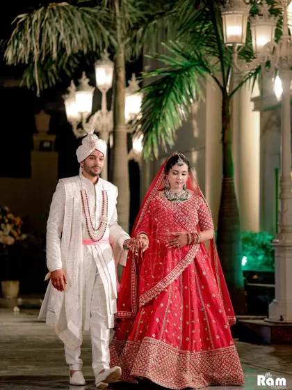 A classic walking shot of the newly married couple, hand in hand, in a grand outdoor setting at night.