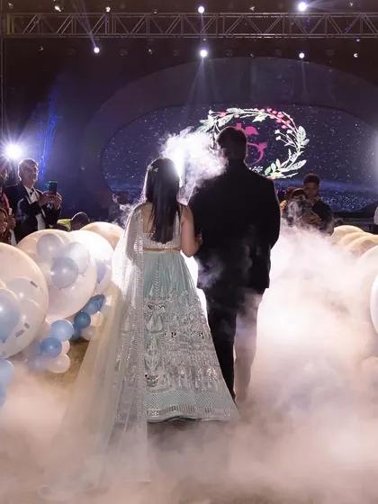 The couple's grand entrance through a cloud of low-lying fog and a pathway of balloons. This creates a dreamy, 'walking on clouds' effect for a truly magical start to their sangeet night.