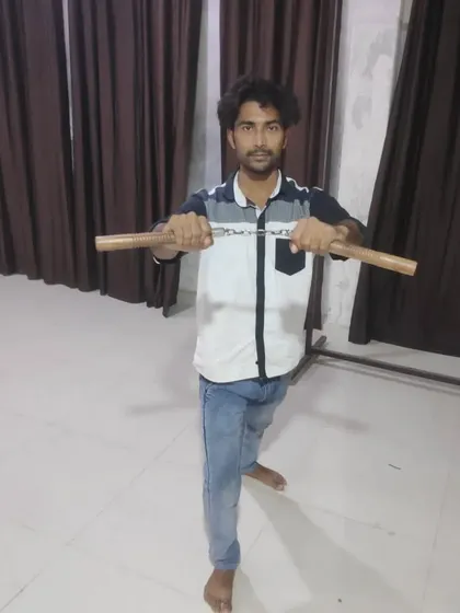 Student Mohd Farman holding the nunchaku. This weapon improves coordination and speed, making it an excellent tool for advanced martial arts training.