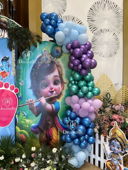 Another angle of the Krishna-themed entrance, with a large footprint cutout and a vibrant balloon column.