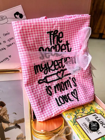 "The secret ingredient is mom's love." A custom-embroidered apron included in a thoughtful care package for a mother.