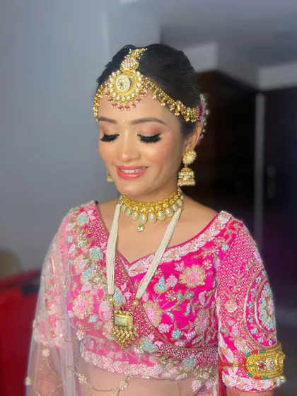 Pooja's smile shows her happiness with her final look. The makeup is perfectly balanced with her ornate jewelry and vibrant outfit.