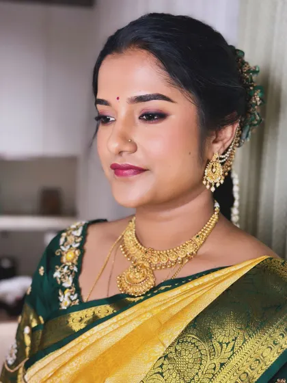 A side profile of Keerthana, showing her classic updo and the subtle glow of her makeup.