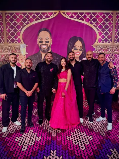 The team with the happy couple at their sangeet in Marrakech. You can see the custom backdrop we created, featuring a cartoon version of the bride and groom.