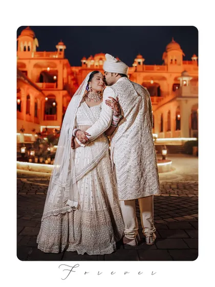 A full-length portrait of the couple, with the groom placing a gentle kiss on the bride's head, framed to feel like a timeless piece of art.
