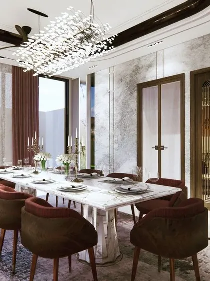 The play of light from the large window and the crystal chandelier illuminates the dining space. The deep red curtains add a touch of drama and color, contrasting beautifully with the marble walls.