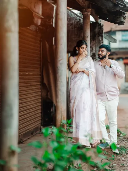 A candid shot of a couple sharing a laugh while walking down a rustic village street, capturing a moment of genuine happiness.