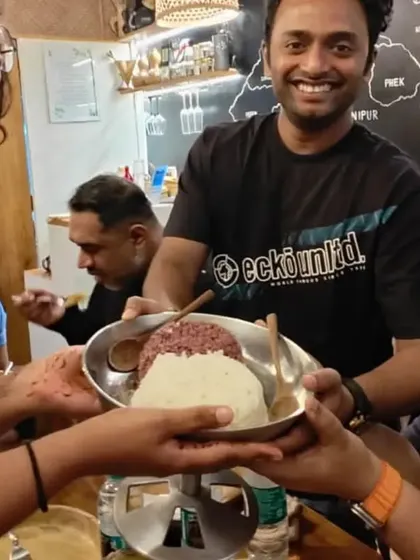 A moment of sharing and laughter as one of our guests is served a bowl of our traditional red and white rice. This is what our community is all about.