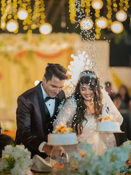 The cake cutting ceremony at a Catholic wedding reception, with confetti adding to the festive and celebratory atmosphere.