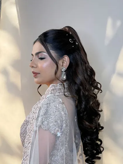 The side profile highlights the beautiful curls and the subtle hair accessories that add a touch of sparkle to her ponytail.