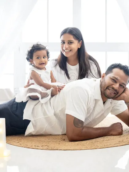 A playful family moment celebrating their daughter's first birthday. The baby is having fun sitting on her dad's back.