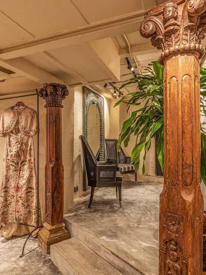 We believe in celebrating materiality and heritage. These graceful vintage wooden columns, salvaged and restored, define the entrance to the changing rooms. They stand against matte greige hand-plastered walls, showcasing our signature blend of raw textures and refined historical elements.