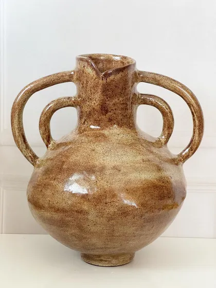 A large, hand-built vase with four handles and a rustic, earthy glaze. This piece has a wonderful, ancient feel to it.