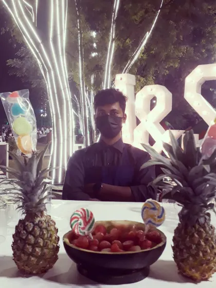 Fun and creative serving ideas for a wedding event. Here, we've set up a station with melon ball vodka shots and colorful lollipops, displayed on pineapples for a playful and tropical touch.