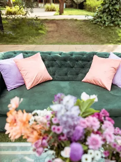 A comfortable and stylish lounge area for guests to relax. The emerald green tufted sofa with pastel cushions provided a pop of color against the natural greenery.