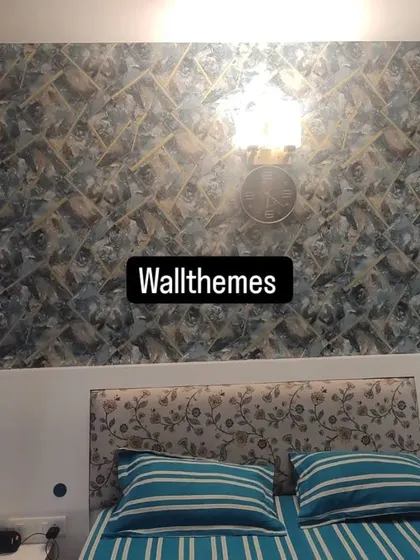 A bold, geometric wallpaper installed as a feature wall behind a bed. The pattern creates a striking 3D effect, making the room feel more dynamic.