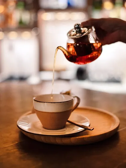 A stream of hot tea being poured from a glass pot into a ceramic cup. It's a ritual of comfort and calm.