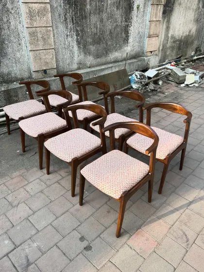 Another view of the set of eight dining chairs, highlighting the consistent grain of the teak wood and the quality of the finish across the entire batch.