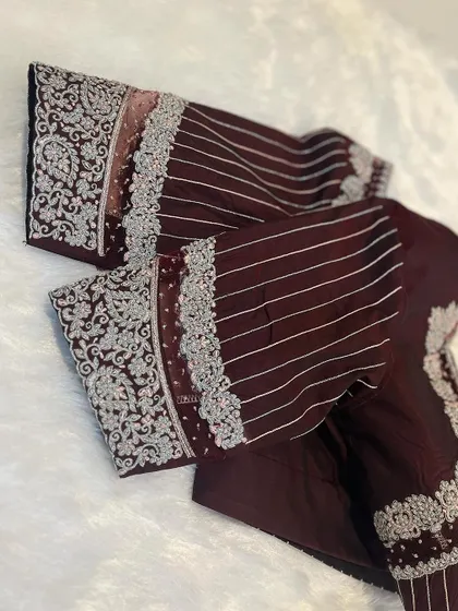 A client's order for a reception blouse in a deep maroon color, with heavy silver embroidery on the sleeves.