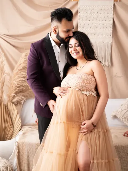A formal and loving portrait. The dad-to-be is dressed in a sharp blazer, perfectly complementing the mom-to-be's elegant beige lace and tulle gown.