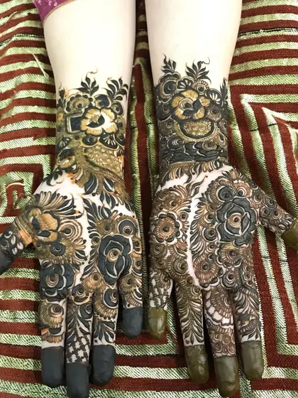 This design shows a mix of fresh henna paste and the developing stain, with bold floral work.