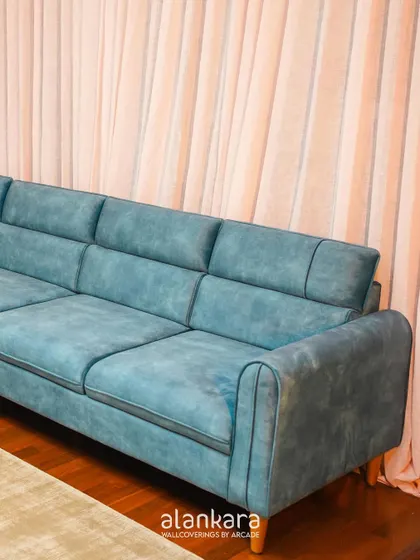 A side view of the blue sofa, highlighting the clean lines, piped edges, and paneled back cushions that define its modern aesthetic.