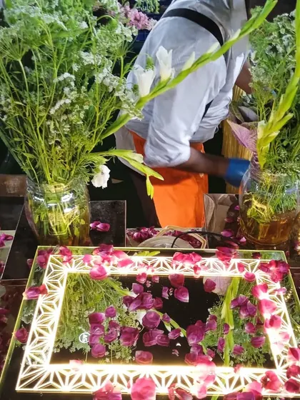 My team setting up a salad station, with an illuminated mirror tray and fresh flowers ready for the food display.