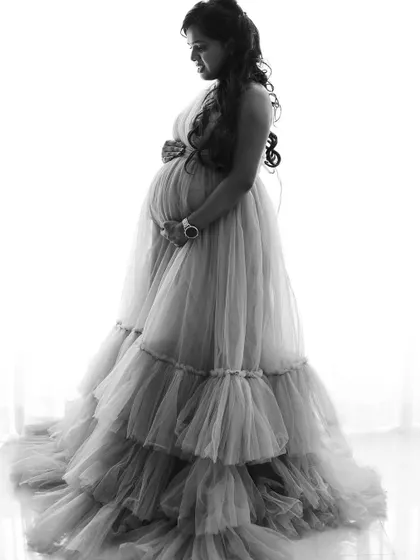 A classic black and white silhouette of a mom-to-be in a ruffled gown, beautifully capturing the shape and texture of the dress.