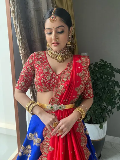 A full view of the red and blue half-saree. The makeup is balanced to complement the bold colors of the outfit.