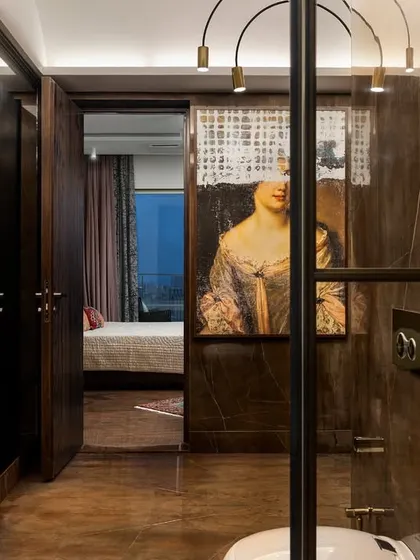 A view from the master bathroom into the bedroom, inspired by vintage elegance. The space features a striking piece of art and delicate hanging lights, offering a moment to restore and indulge.