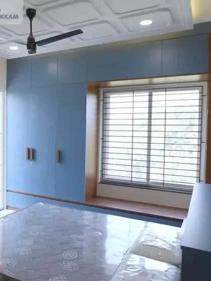 The son's bedroom in the Ayyapakkam villa, designed with a calming blue theme, a window-side seating area, and a coffered false ceiling.