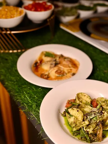 Two different pasta dishes prepared at our live station, one with a pesto sauce and the other with a classic tomato-based sauce, showing the variety we offer.