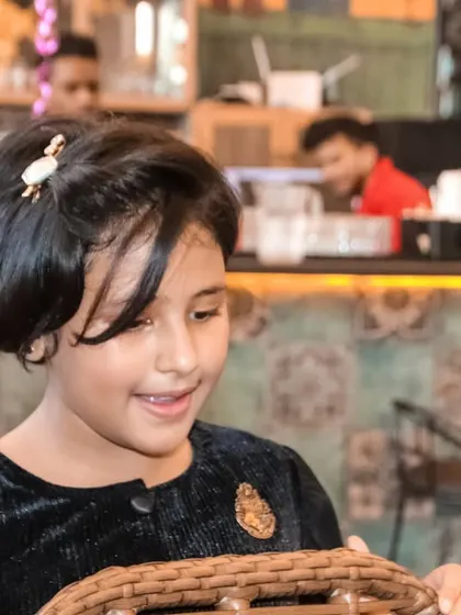 A candid shot of a young girl smiling as she looks into a basket during a party.