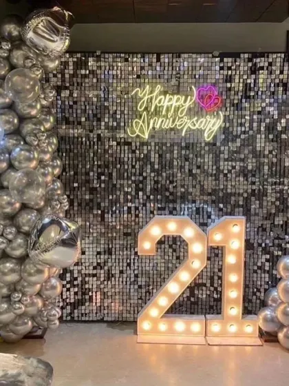 A sparkling 21st anniversary party with a silver sequin wall, chrome balloons, and large marquee numbers. It's a glamorous way to celebrate a special milestone.