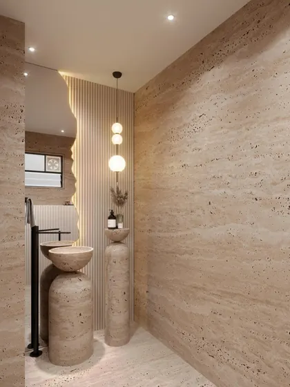 This powder room concept uses travertine stone to create a warm, earthy, and monolithic feel. The design features a sculptural pedestal sink and an organically shaped mirror, blending natural materials with modern forms.
