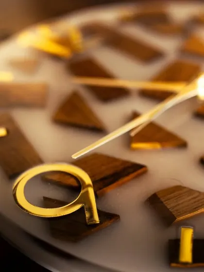 A close-up shot of the wood and resin clock, highlighting the texture of the teak wood blocks against the smooth, milky-white resin. The golden '9' adds a stylish detail to the piece.