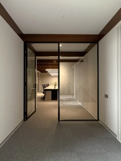 The entrance to a main conference room, framed by black metal and glass. This design choice creates a visual connection to the corridor, making the entire floor feel more open and accessible.