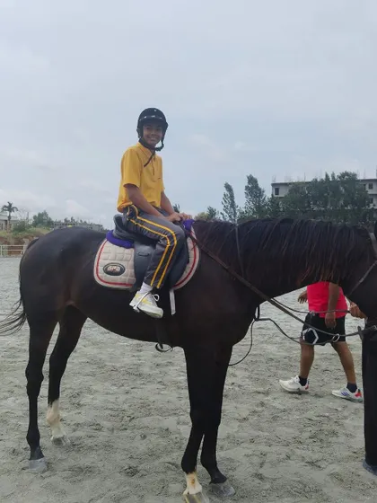 A smiling student sits confidently atop his horse, enjoying the unique experience and life skills that our equestrian program offers.