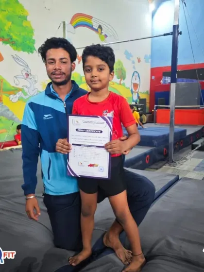A young gymnast proudly holds his certificate with his coach. We believe in recognizing every achievement to build confidence and motivate our athletes.