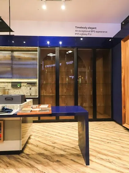 This showroom kitchen demonstrates a bold use of color and materials. A deep blue finish is paired with natural wood and glass cabinets, creating a striking and contemporary design.