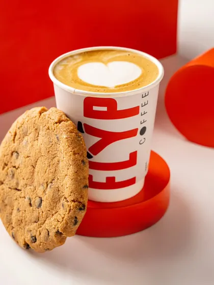 A simple and clean composition for Flyp Coffee, pairing their branded cup with a chocolate chip cookie. This type of shot is perfect for social media and menu highlights.