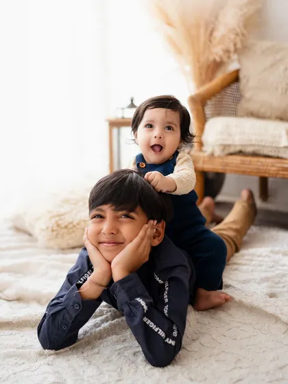 The best kind of playground! This playful shot of a baby riding on his big brother's back is full of laughter and sibling love.