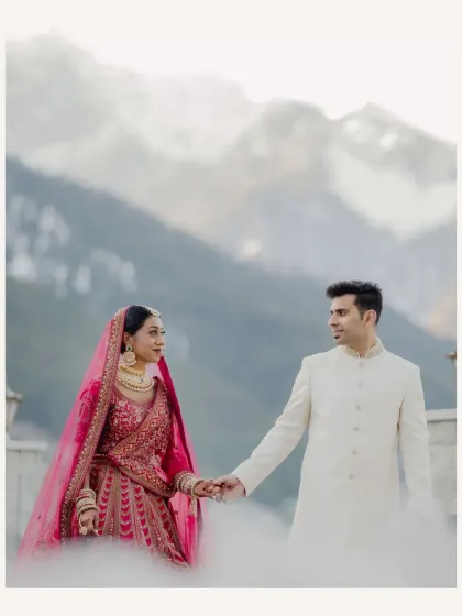 The couple holds hands, their figures framed by the snow and mountains. A beautiful, serene moment from their destination wedding.
