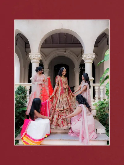 The bride surrounded by her tribe. Her bridesmaids help arrange her stunning lehenga, creating a beautiful, supportive, and picture-perfect moment.