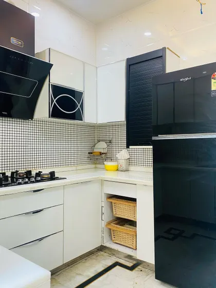 An overall view of the black and white kitchen, showing the placement of the refrigerator and the efficient use of space in a compact U-shaped layout.