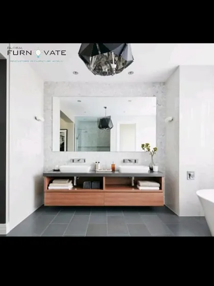 A luxurious bathroom with a double vanity, a large mirror, and a freestanding bathtub. The dark flooring and wooden vanity add warmth to the white marble walls.
