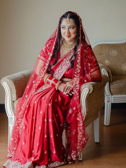 A full-length portrait of the bride in her red saree, looking elegant and poised.