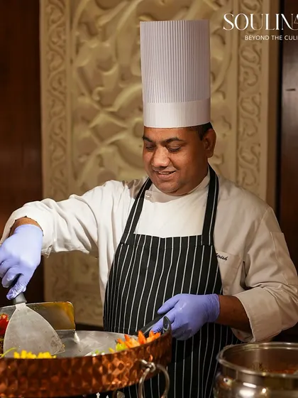 A smiling chef prepares a dish at a live Tawa station, showcasing the joy and passion our team brings to their craft. We believe in service with a smile.