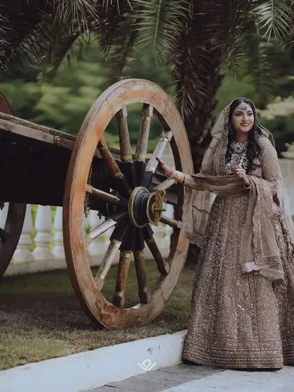 A unique bridal portrait with the bride posing next to a rustic wooden cart, blending tradition with a vintage element.