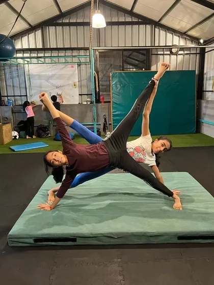 Two students demonstrate a synchronized side plank variation, a partner exercise that builds core strength, stability, and coordination.